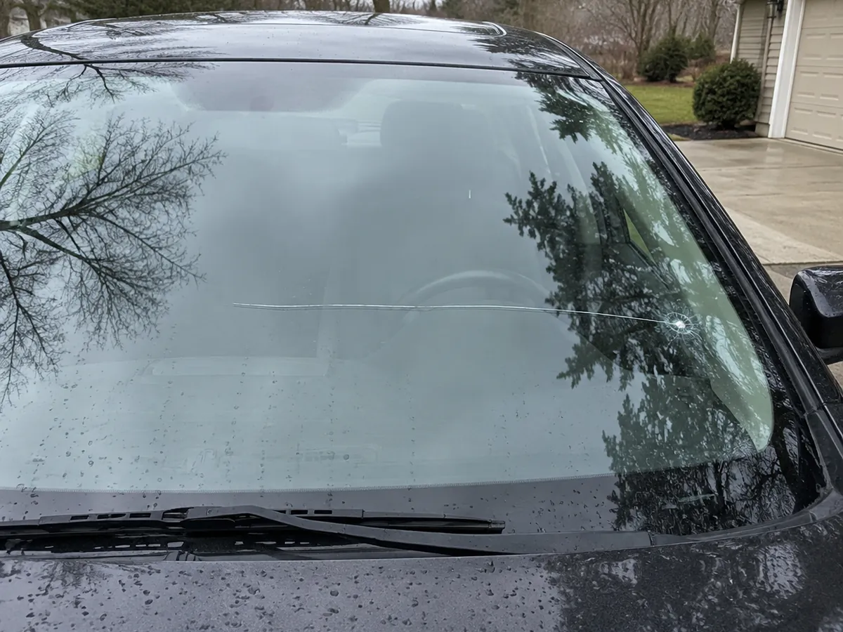Cracked windshield with a rock chip and a crack spreading across the glass